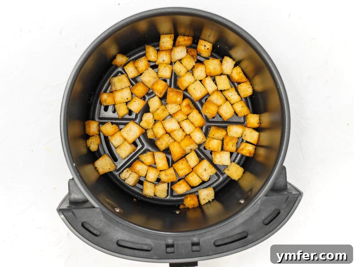 Golden Crunch Air Fryer Croutons 7 diced bread in air fryer basket. Seasoned bread cubes are spread out in an air fryer basket.