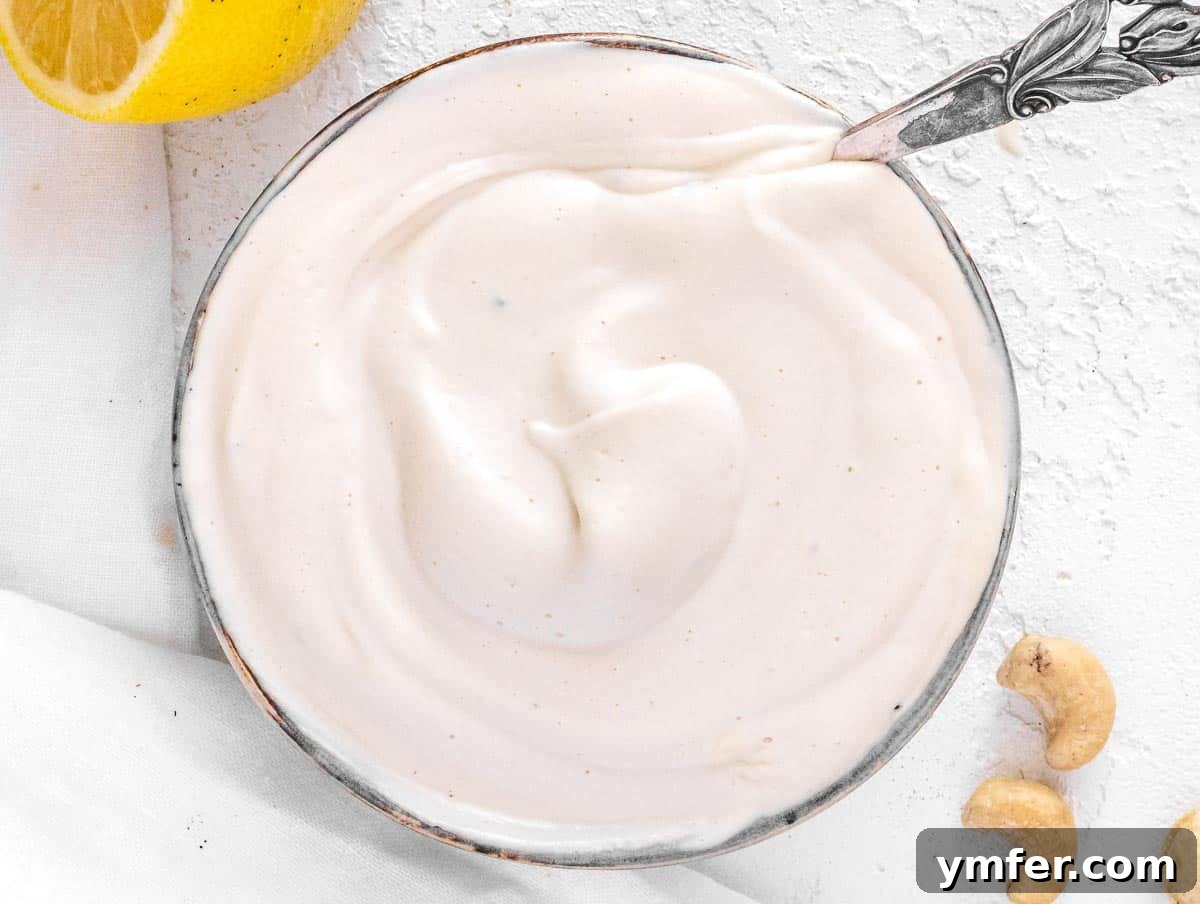 Velvety Vegan Sour Cream 12 A bowl of vegan sour cream with a silver spoon, highlighting its smooth texture.