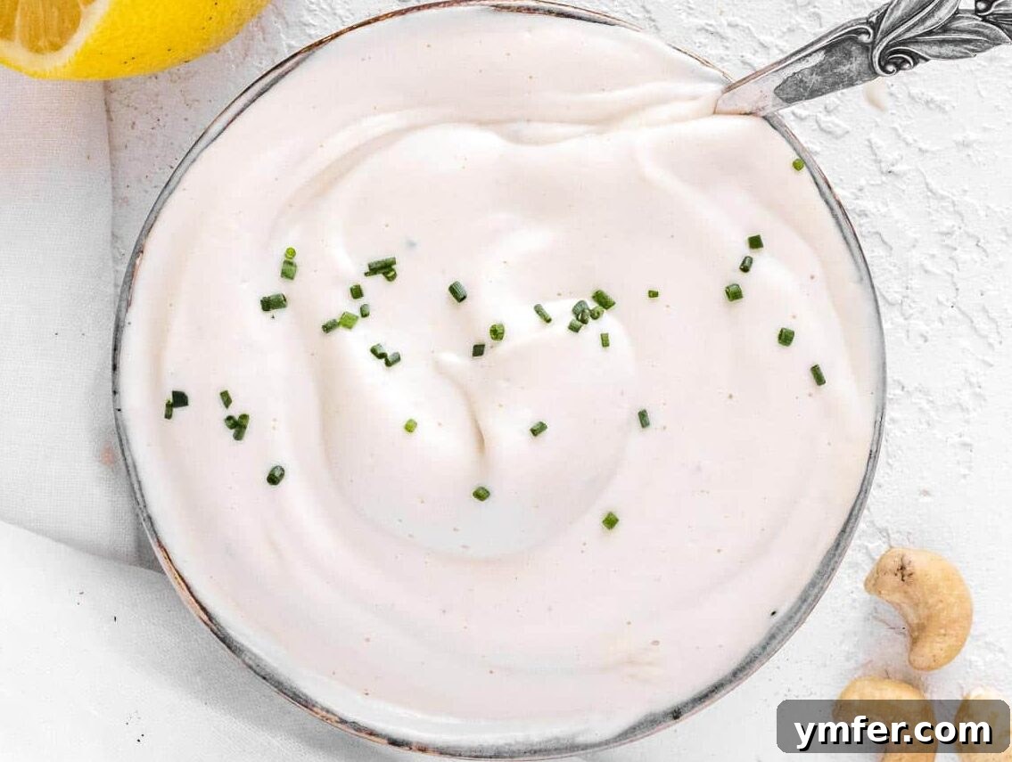 Velvety Vegan Sour Cream 7 A bowl of freshly made vegan sour cream garnished with finely chopped chives and a lemon wedge.