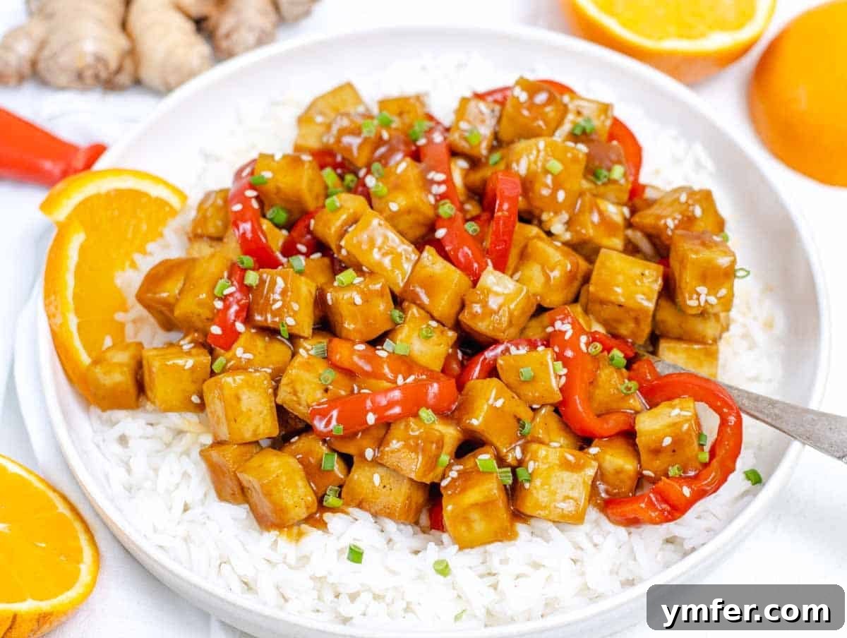 35 Vibrant Vegetarian Lunch Ideas 28 Crispy orange tofu served on a plate with fluffy rice and a spoon.