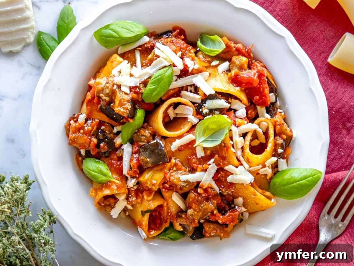 35 Vibrant Vegetarian Lunch Ideas 3 Eggplant pasta with a rich tomato sauce, fresh basil, and a sprinkle of cheese in a white bowl.