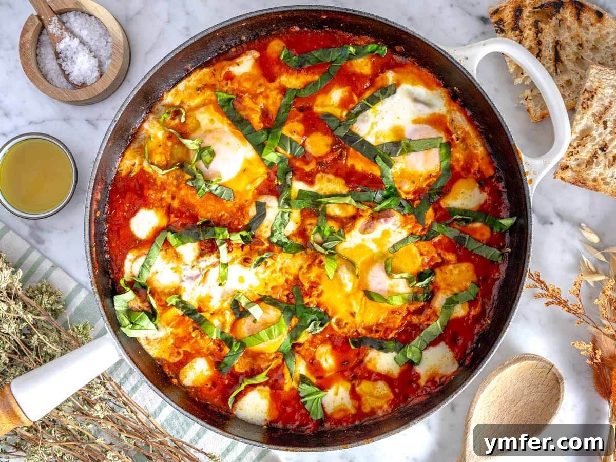 35 Vibrant Vegetarian Lunch Ideas 6 Eggs in purgatory, a rustic Italian dish, served in a white skillet with fresh basil.