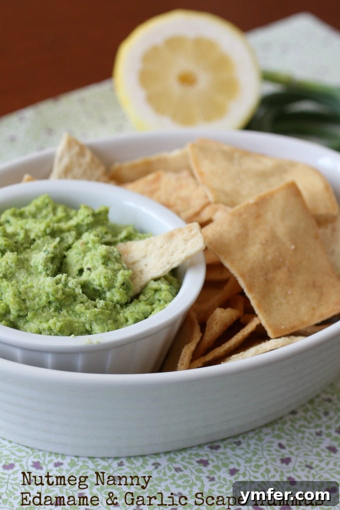Edamame & Garlic Scape Hummus Edamame Garlic Scape Hummus in a dish with pita chips.