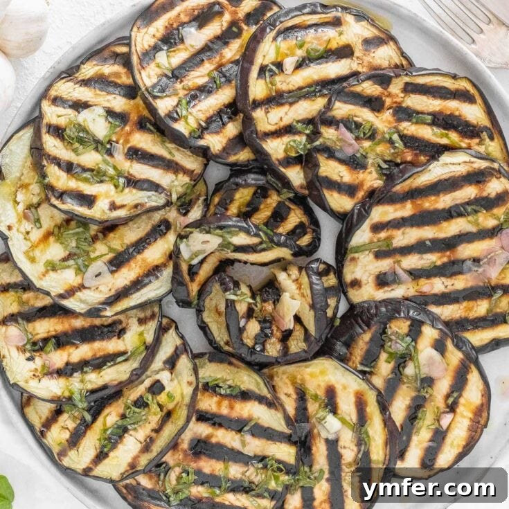 Grilled eggplant slices on a platter with herbs.