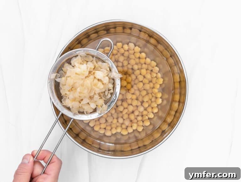 fishing the chickpea skin out of the bowl