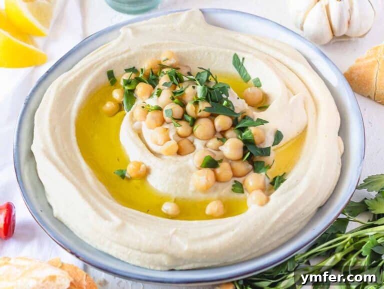 Hummus recipe on a plate with lemon and pita bread on the side