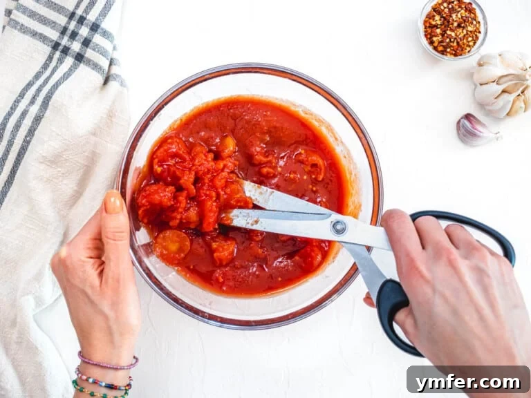 Rustic Marinara 21 hand using scissors to cut whole peeled tomatoes