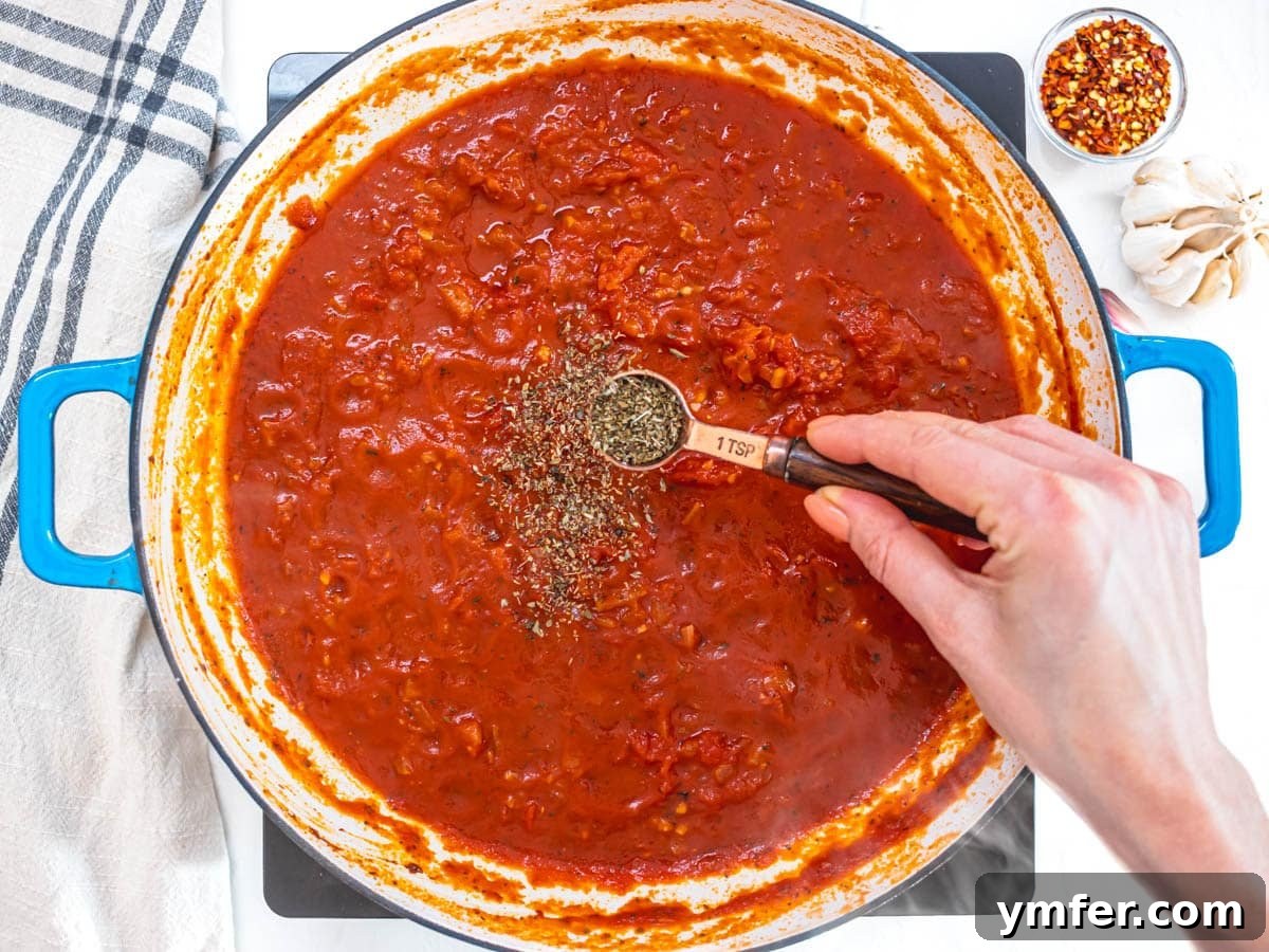Rustic Marinara 9 hand adding oregano to marinara sauce