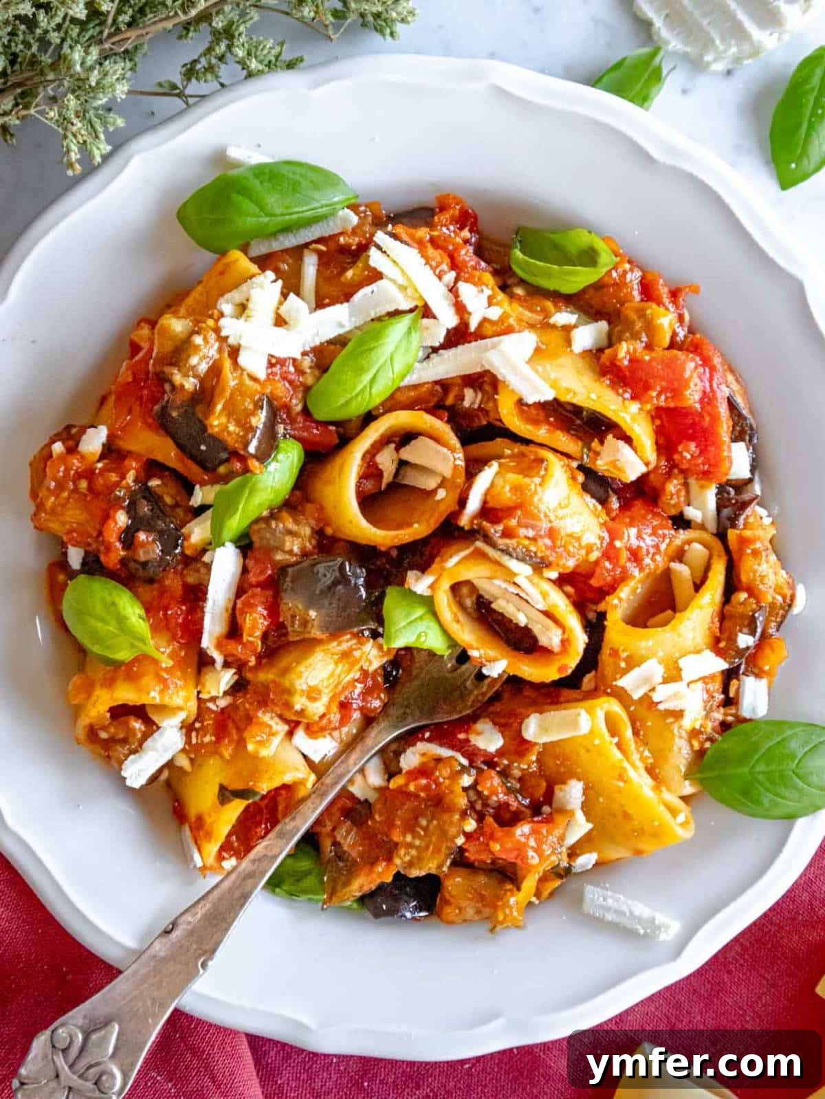 Sicilian Eggplant Pasta Delight 2 Pasta alla Norma with roasted eggplant tomato sauce and basil on a dinner plate.