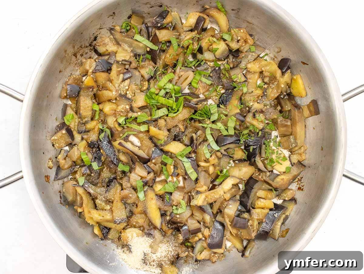 Sweet and Tangy Glazed Eggplant 8 Finely chopped fresh herbs being added to the cooked eggplant in the pan.