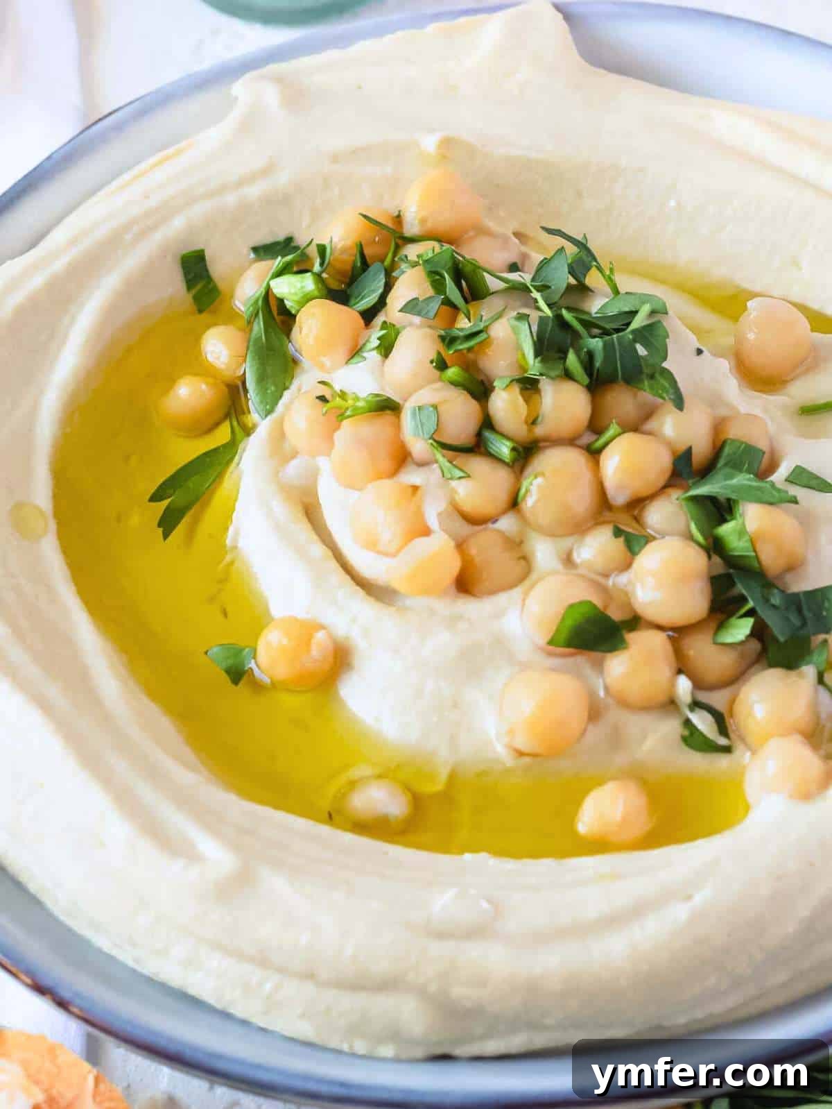 The Art of Hummus 2 A bowl of freshly made, creamy hummus, garnished with olive oil, chickpeas, and fresh parsley, ready to be served.
