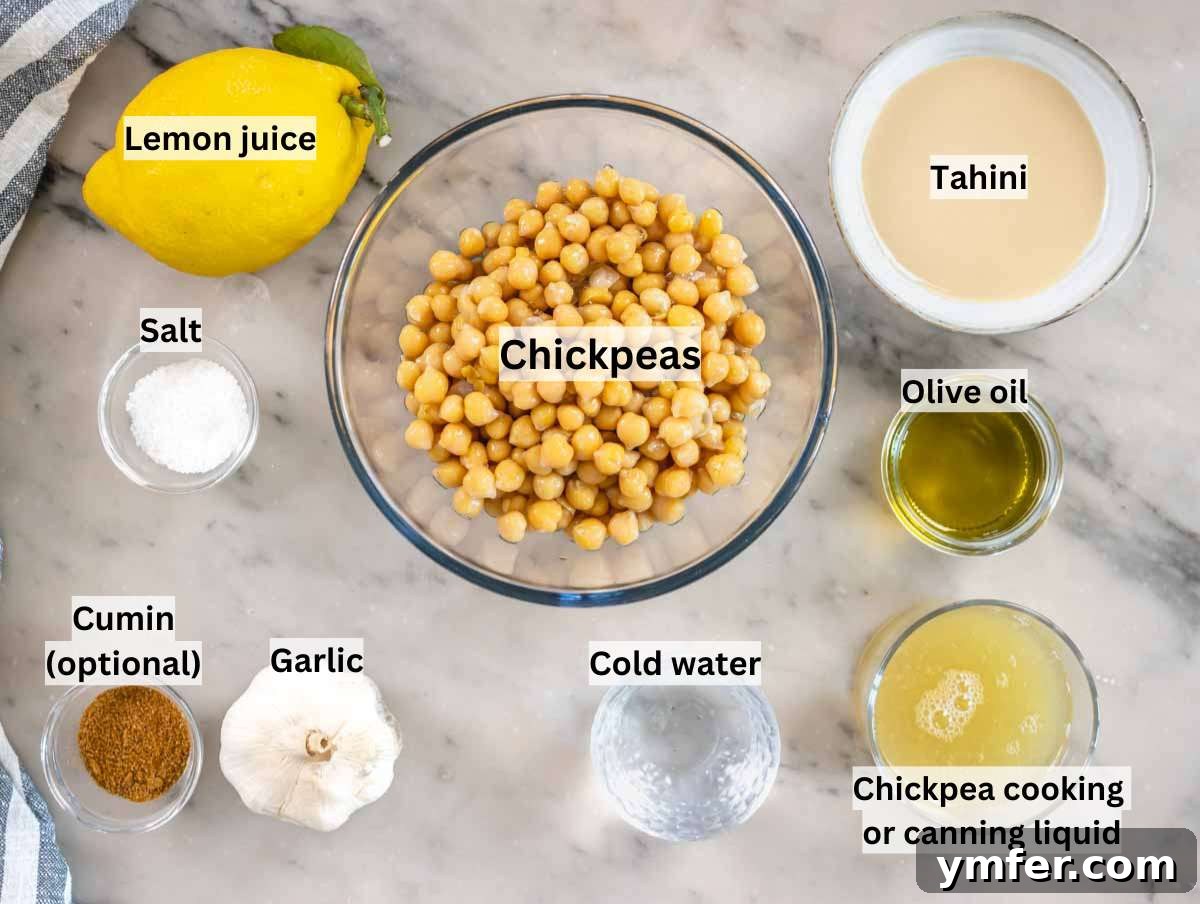 The Art of Hummus 3 A beautiful flat lay of fresh hummus ingredients on a marble table, including chickpeas, tahini, lemon, garlic, olive oil, and baking soda.