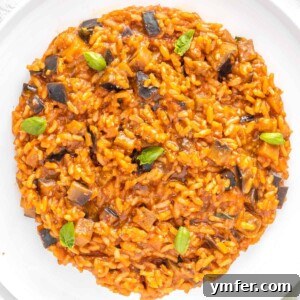 Eggplant risotto served in a rustic bowl, garnished with fresh basil leaves.