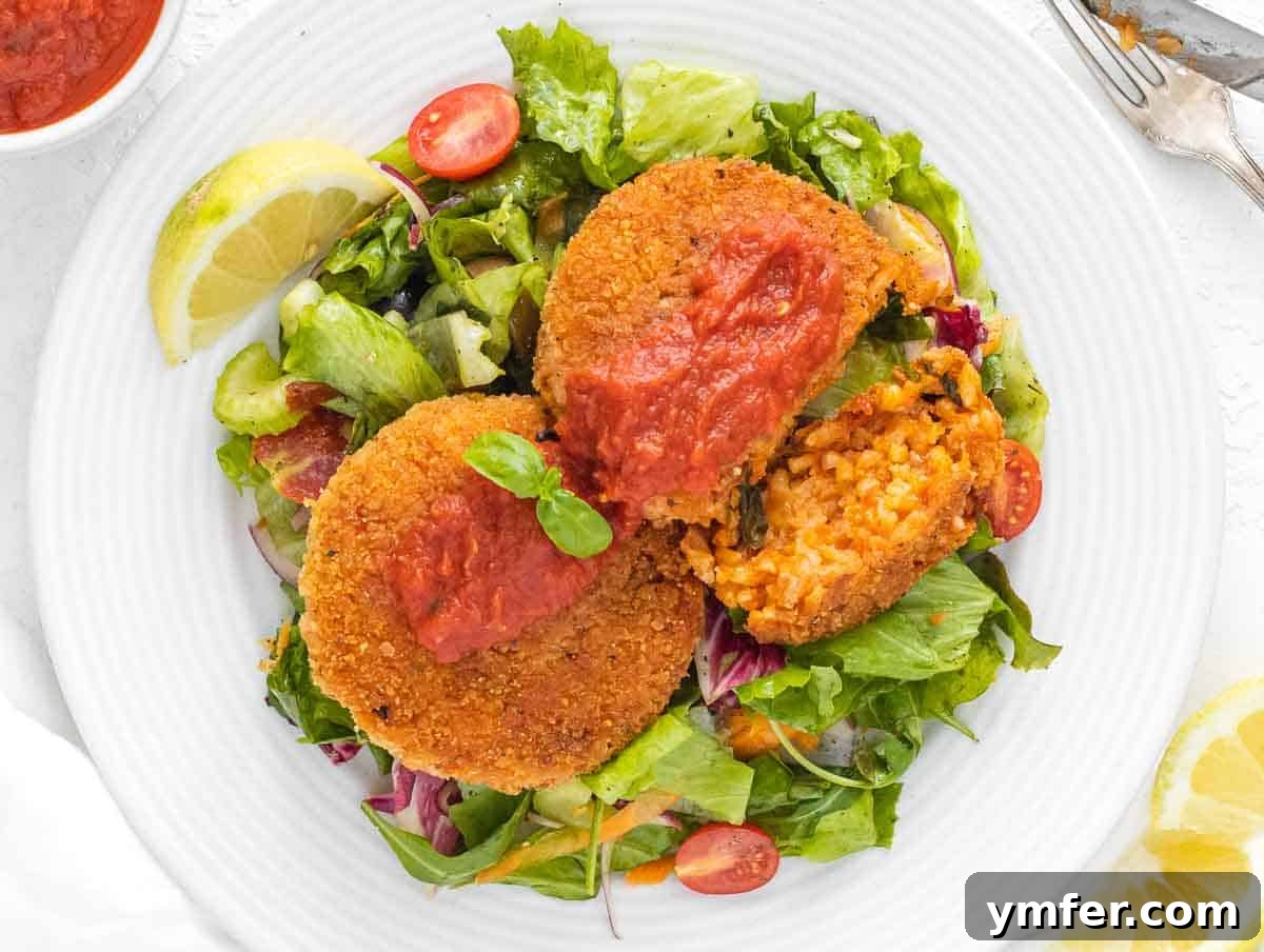 Arancini 3 Cut open risotto cake revealing creamy interior, served with a side of rich marinara sauce.