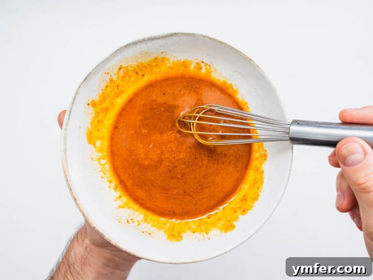 Moroccan Spiced Carrot Salad 7 harissa dressing in a small bowl with hands and a whisk
