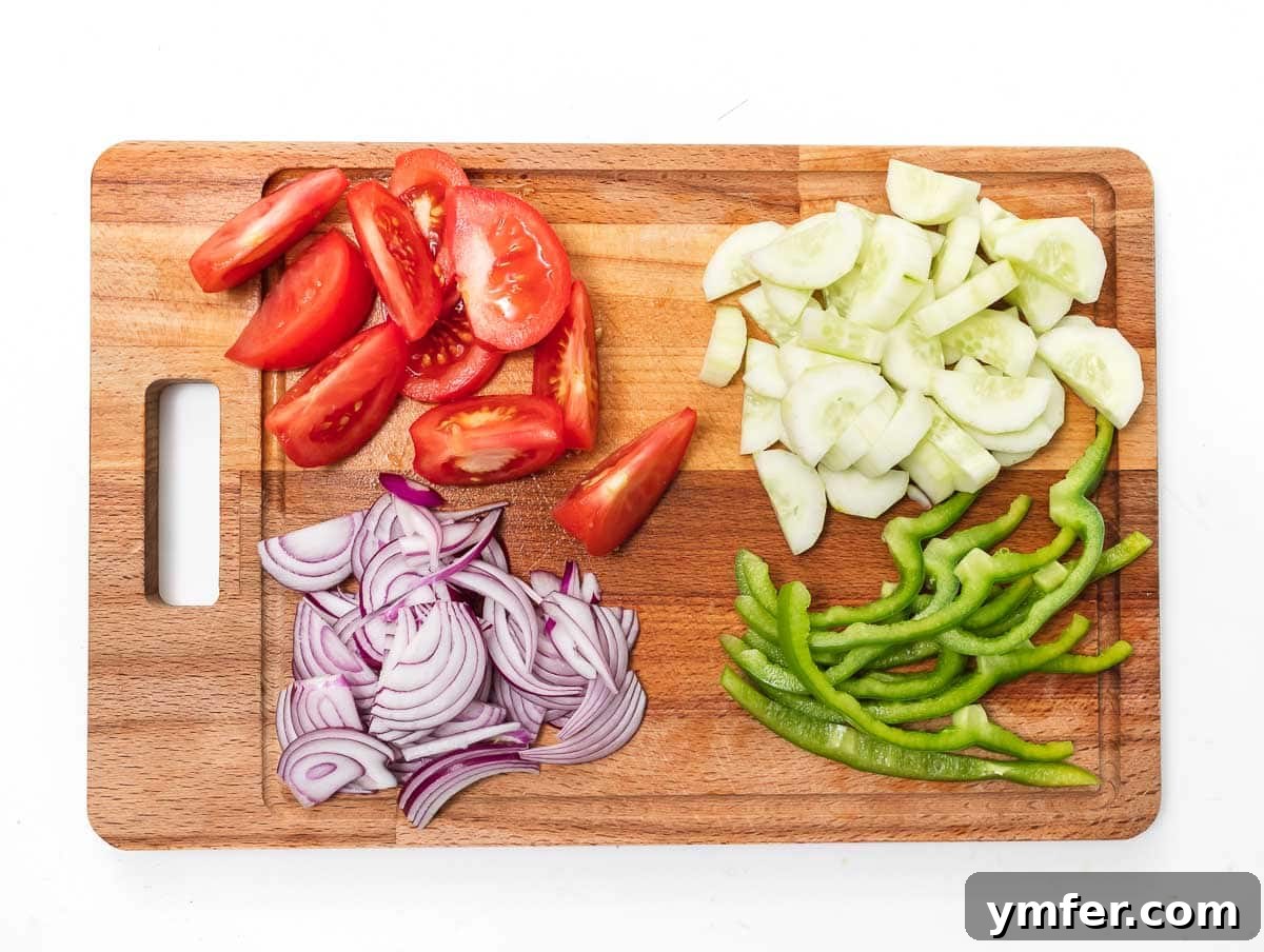 Horiatiki: The Quintessential Greek Village Salad 6 tomatoes, cucumber, red onion, and green pepper chopped on a cutting board