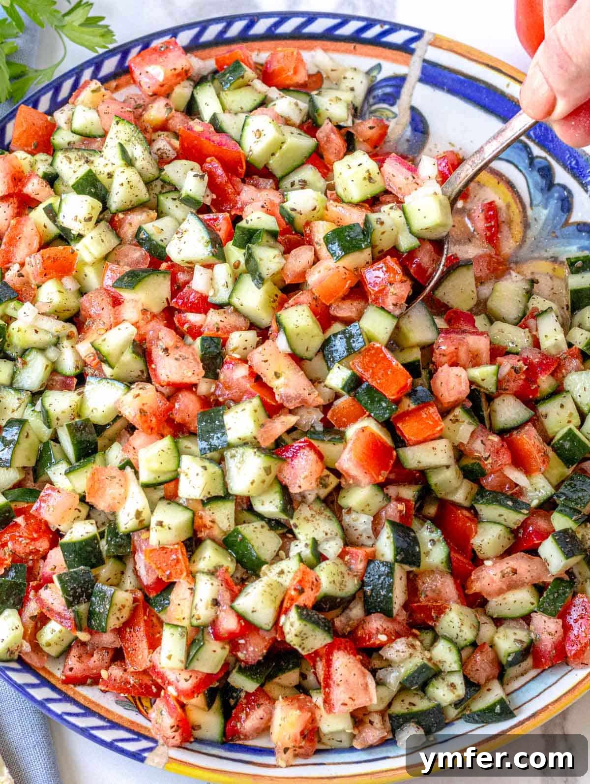 Vibrant Shirazi Chopped Salad 2 Shirazi salad on a blue plate with hand holding a spoon