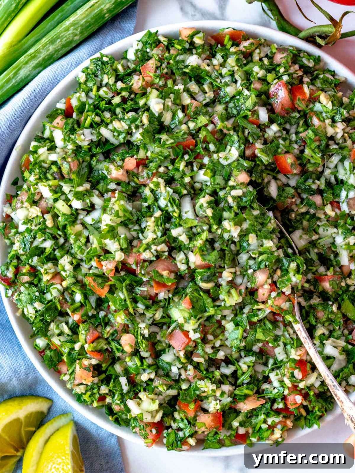 Fresh and Zesty Tabbouleh Salad 2 Overhead view of tabouli (tabbouleh) salad served in a white bowl, garnished with lemon slices and romaine lettuce leaves, showcasing its fresh, vibrant ingredients.