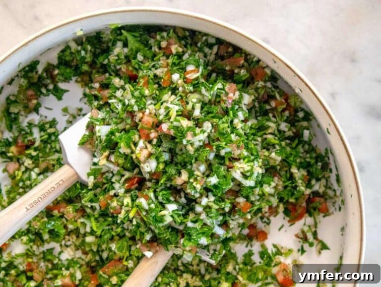 Fresh and Zesty Tabbouleh Salad 12 Mixing bowl with tabouli ingredients being tossed with olive oil and lemon juice for a healthy summer salad.