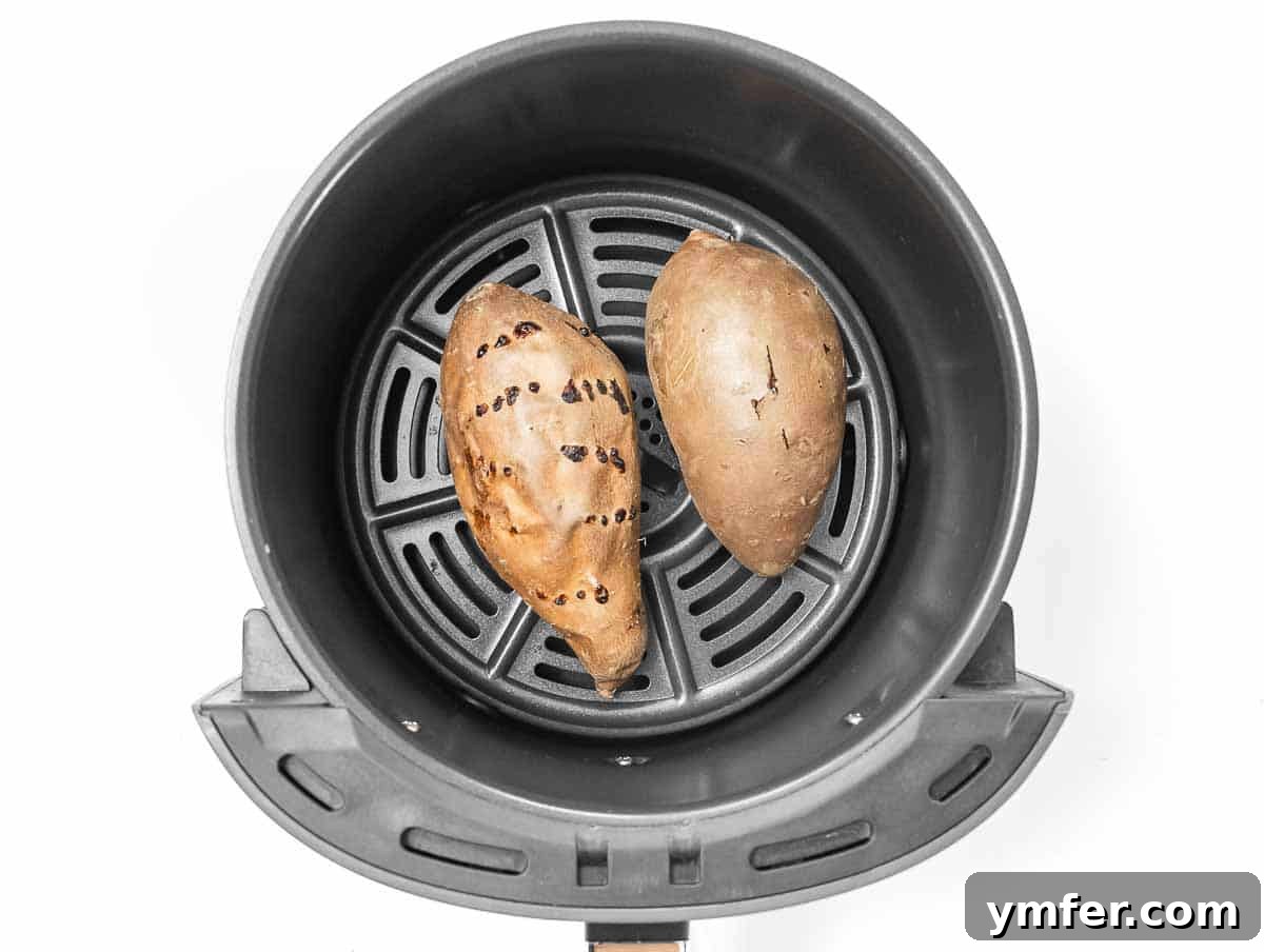 Golden & Crispy Air Fryer Sweet Potatoes 11 Whole sweet potatoes in an air fryer basket, ready to be cooked.
