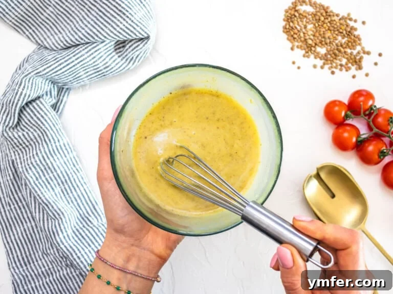 Hearty Lentil & Cauliflower Bowl 15 Cumin and honey mustard dressing in a bowl with a whisk
