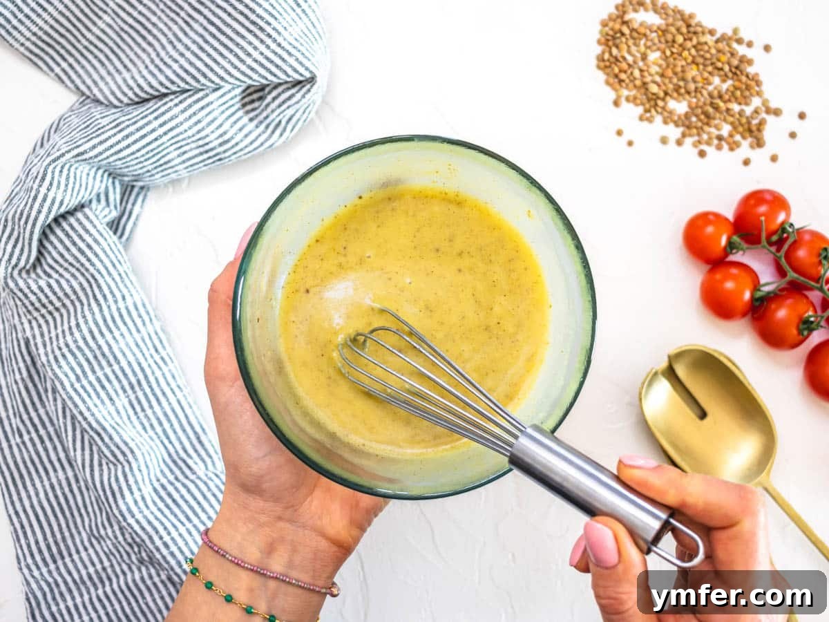 Hearty Lentil & Cauliflower Bowl 6 Cumin and honey mustard dressing in a bowl with a whisk