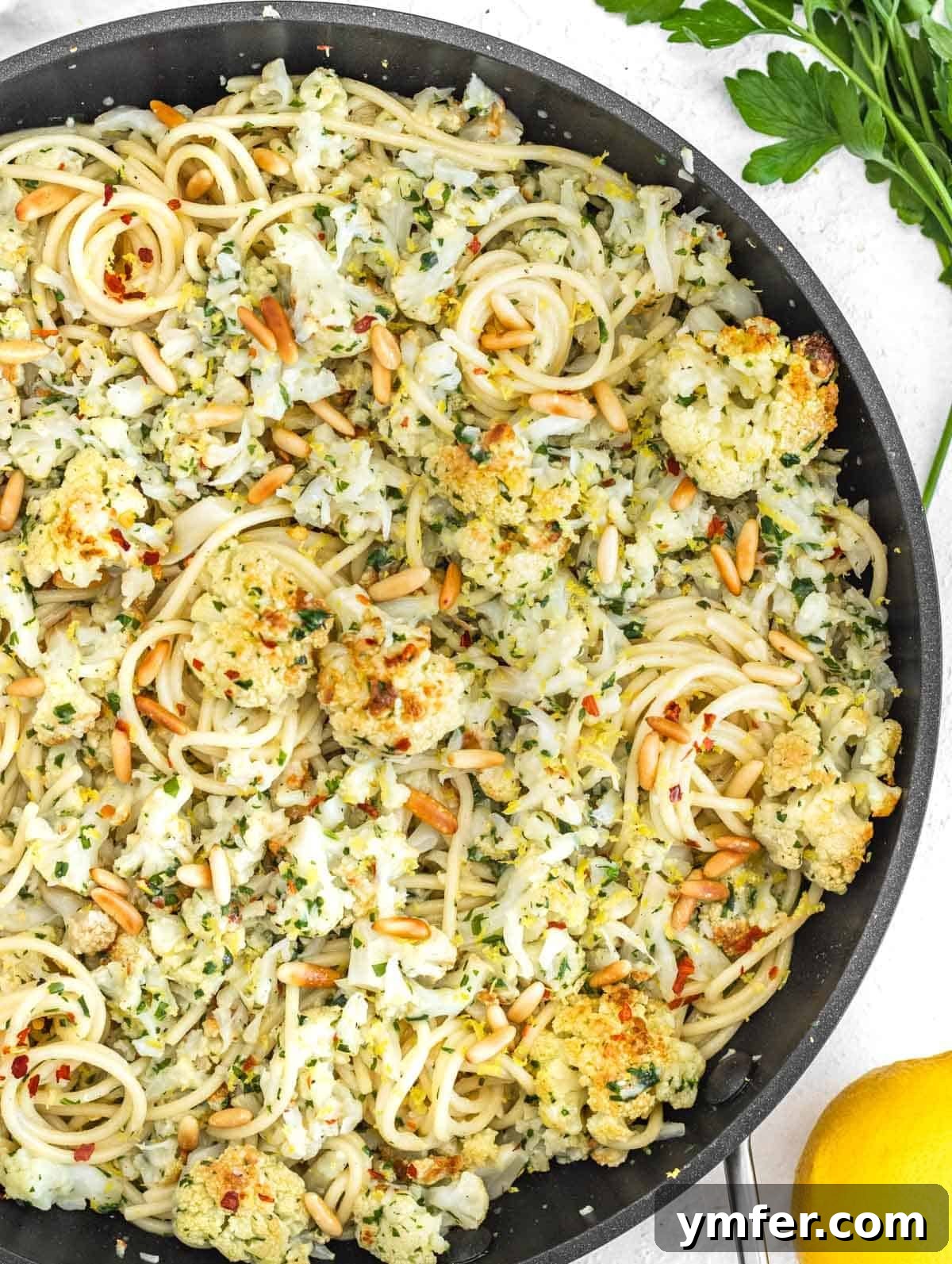 Velvety Cauliflower Pasta 2 Cauliflower pasta in a skillet, garnished with fresh herbs and pine nuts.