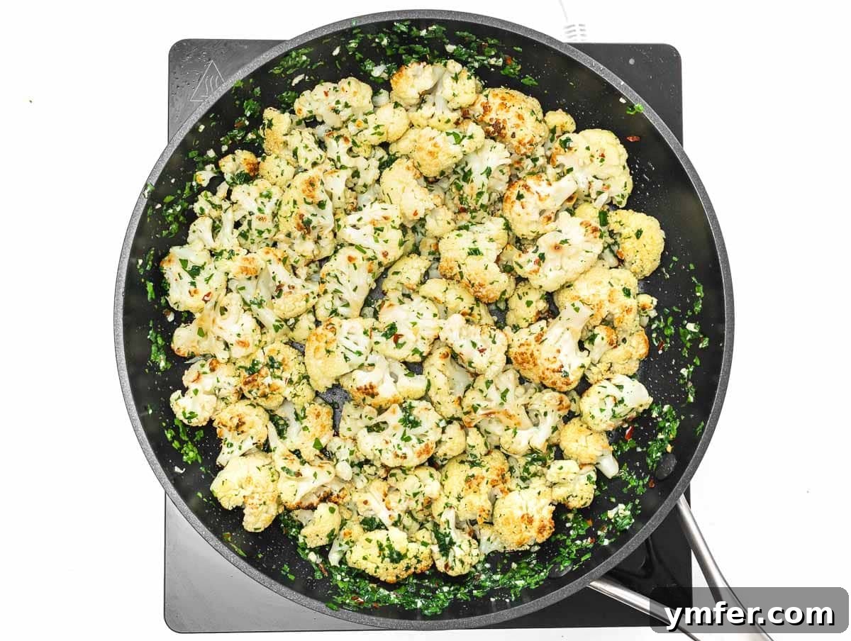 Velvety Cauliflower Pasta 9 Roasted cauliflower florets being tossed with the garlic and oil sauce in a skillet.