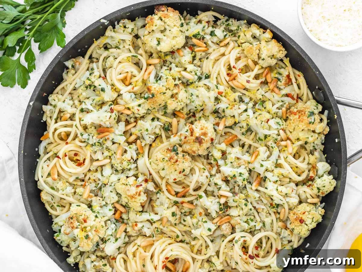 Velvety Cauliflower Pasta 4 A close-up of roasted cauliflower pasta with toasted pine nuts and fresh parsley.