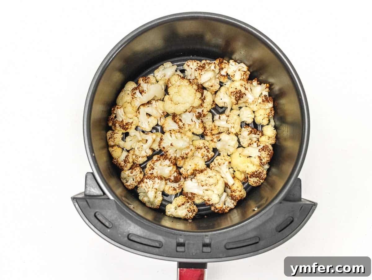 Velvety Cauliflower Pasta 6 Air-fried cauliflower florets in an air fryer basket, golden brown and crispy.