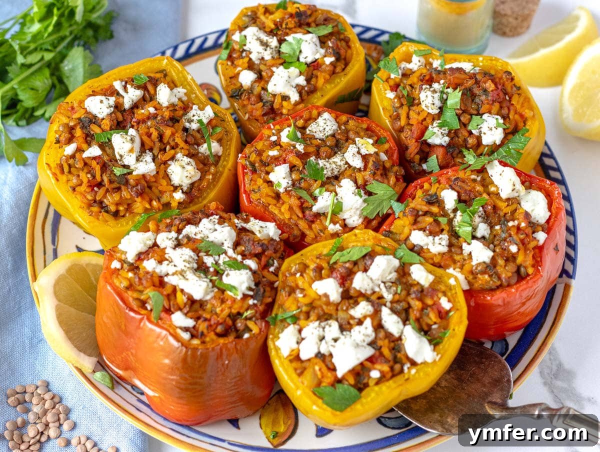 Hearty Lentil Harvest 30 Wholesome Recipes 17 Stuffed bell peppers sprinkled with crumbled feta cheese, presented on a white plate.