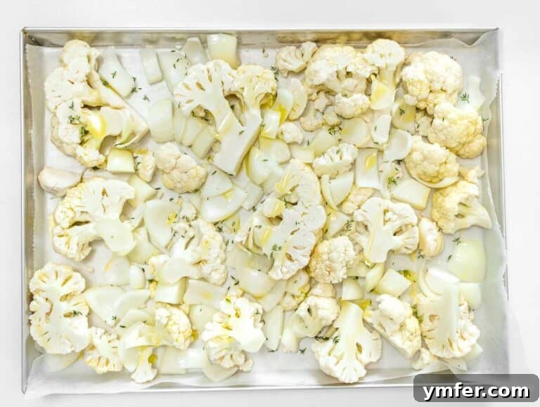 Cauliflower, onion, and garlic prepared on a baking tray for roasting