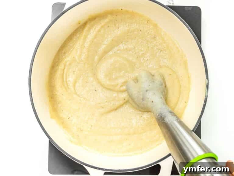 Cauliflower soup being blended directly in a pot with an immersion blender