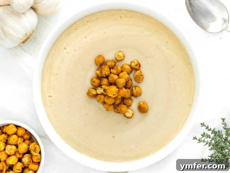 Cauliflower soup served in a bowl, garnished with roasted chickpeas