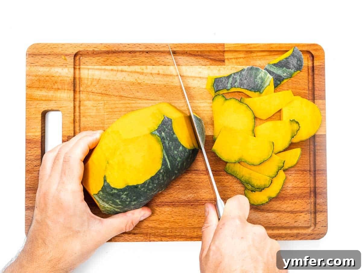 Golden Roasted Kabocha 11 A cook carefully peeling a halved kabocha squash with a sharp knife on a wooden cutting board.