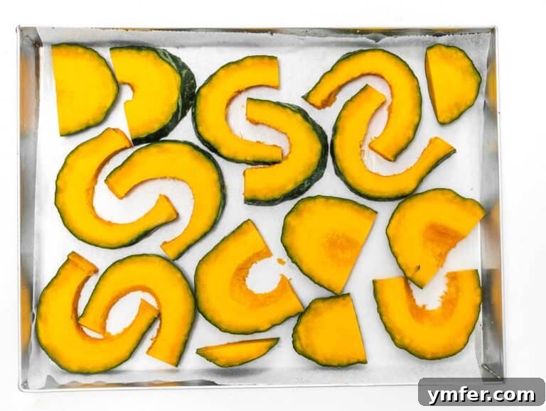 Golden Roasted Kabocha 7 Freshly sliced kabocha squash wedges arranged in a single layer on a parchment-lined baking tray, ready for seasoning.