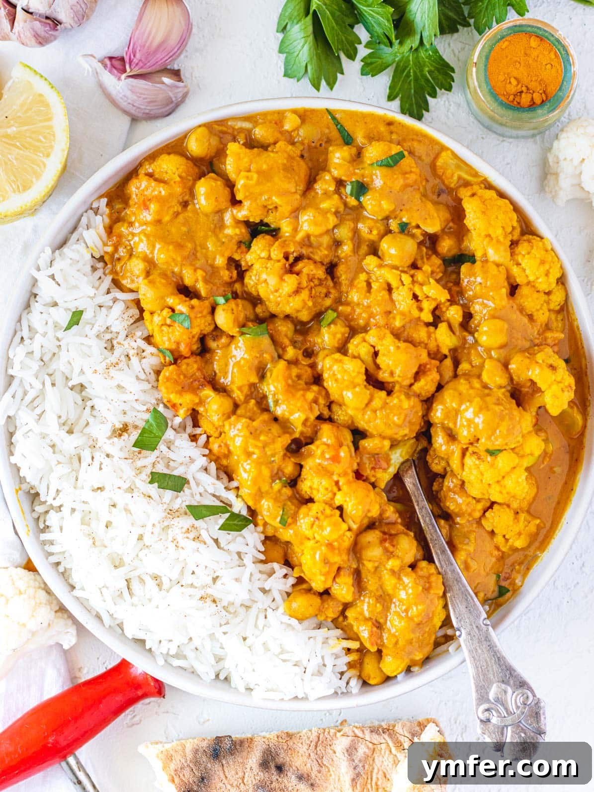 Golden Cauliflower Curry 2 Cauliflower Curry with a silver spoon, garnished with fresh cilantro, ready to be served over rice.