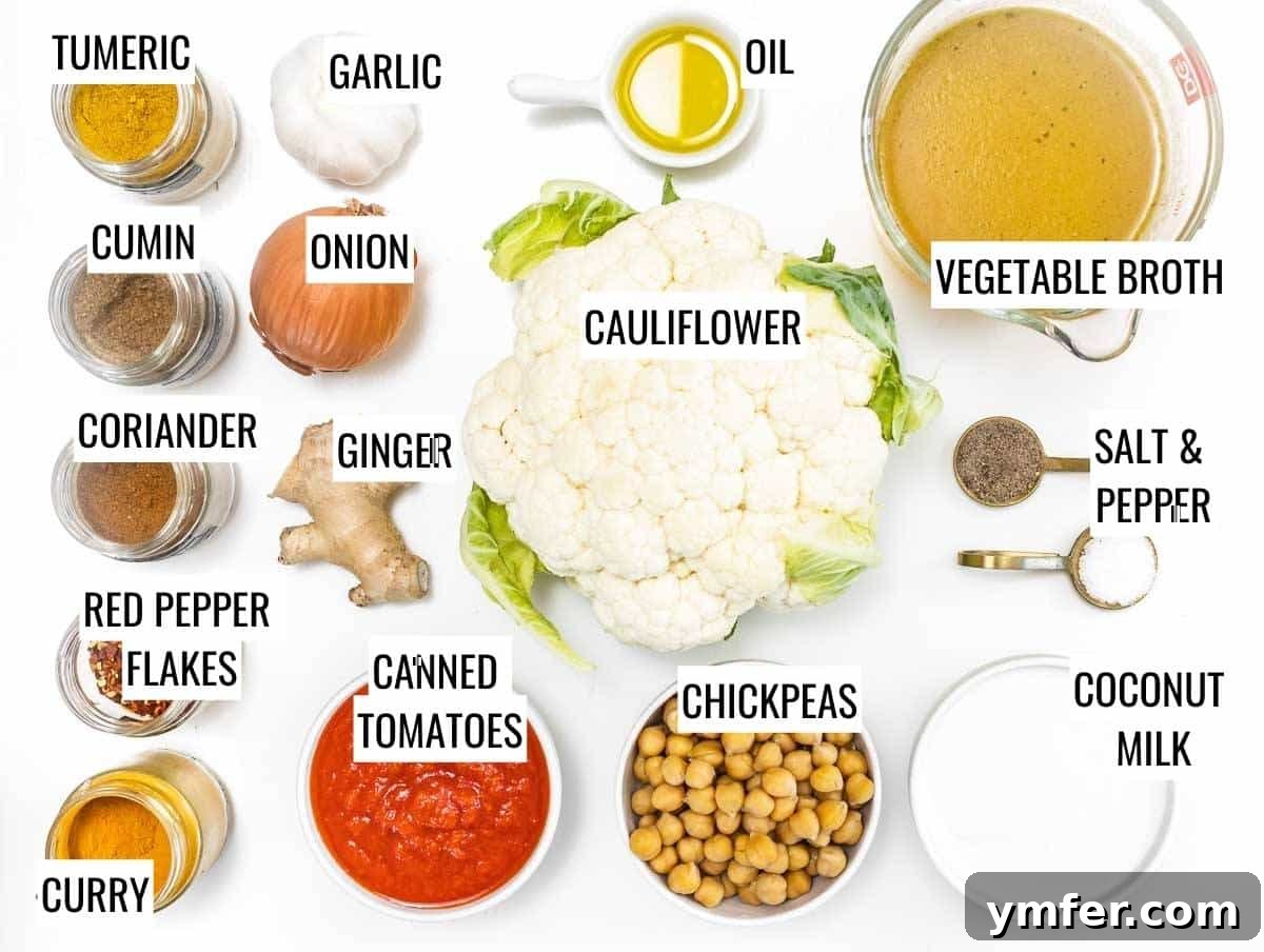 Golden Cauliflower Curry 3 Assorted cauliflower curry ingredients laid out on a wooden surface, including fresh cauliflower, canned goods, and various spices.
