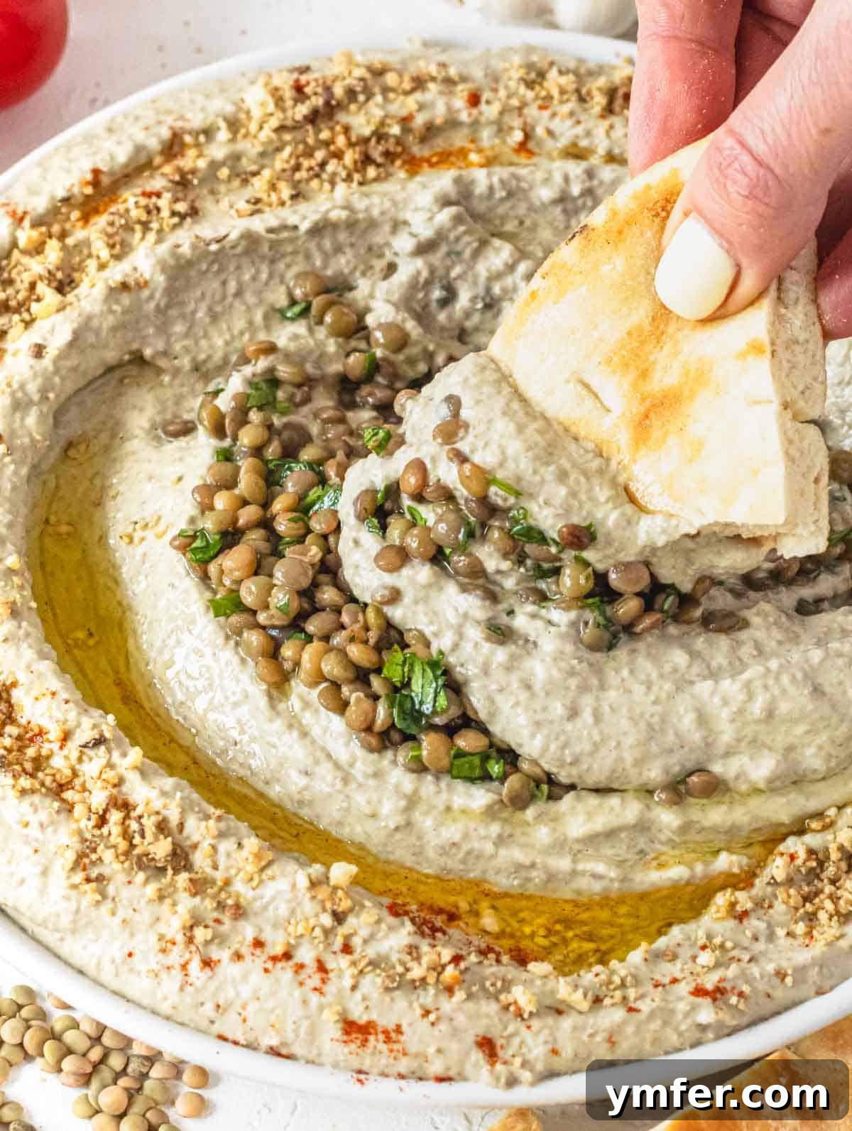 Lentil hummus with hand holding a piece of pita
