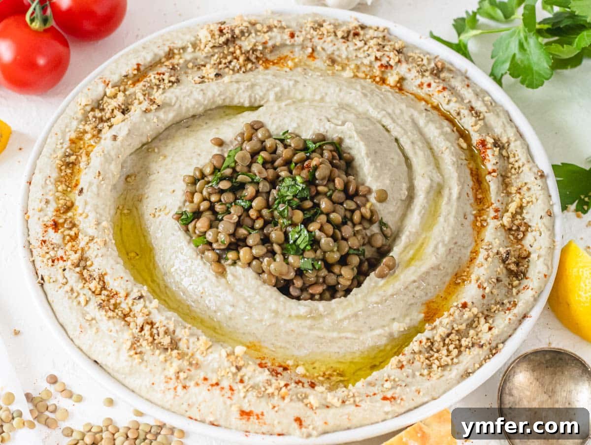 creamy lentil hummus on a plate topped with dukkah and lentils
