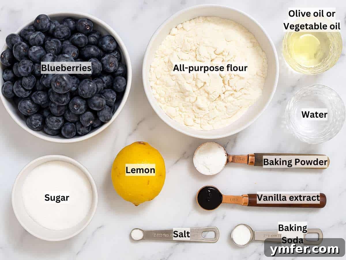 Fresh ingredients for a homemade blueberry tart laid out on a marble table.