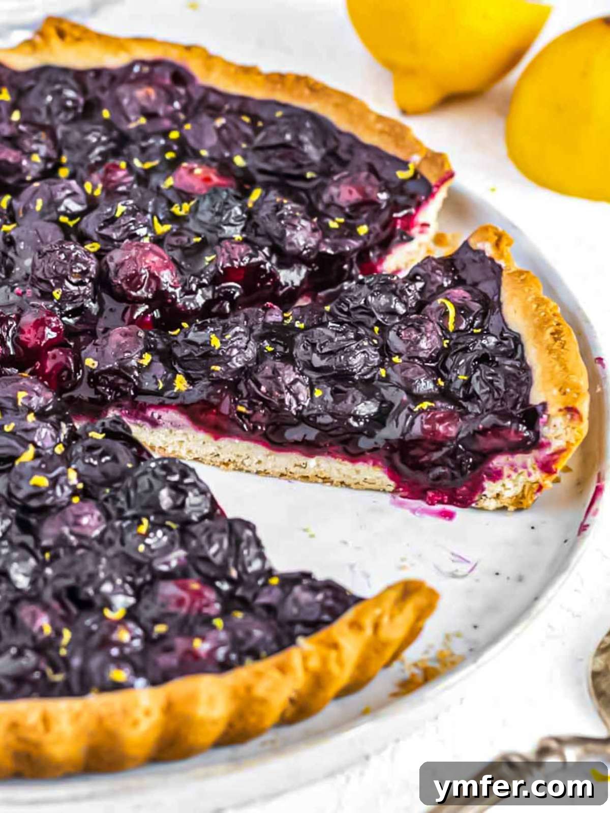 A freshly baked blueberry tart, sliced to reveal the vibrant, jammy blueberry filling.