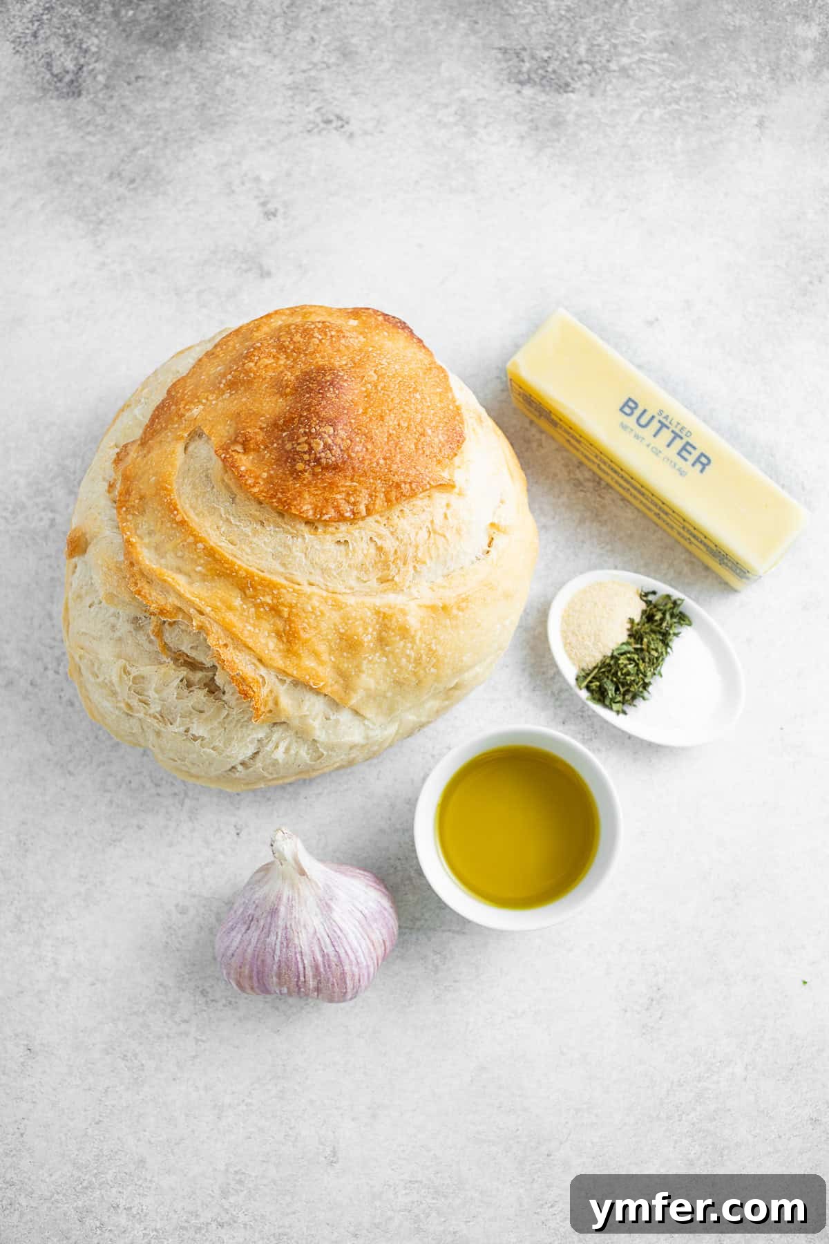 Gathering the key ingredients for flavorful garlic butter croutons. Essential ingredients for homemade croutons: sourdough bread, butter, olive oil, fresh garlic, kosher salt, Italian seasoning, and garlic powder arranged on a kitchen counter.