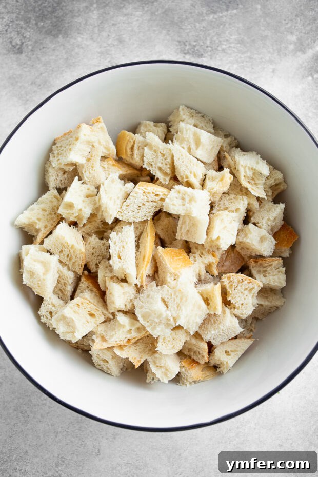 Cubed sourdough bread, the foundation for perfect croutons. Sourdough bread cut into uniform 1-inch cubes and placed in a large mixing bowl, ready for seasoning.