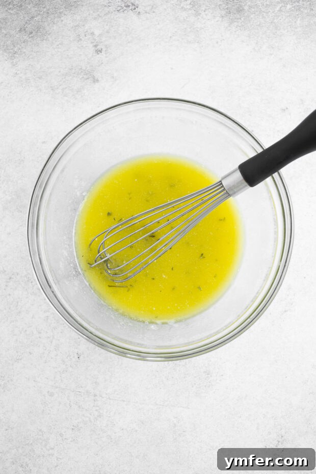 The secret to flavor: melted garlic butter. A small white bowl containing the freshly prepared garlic butter mixture, glistening and aromatic.