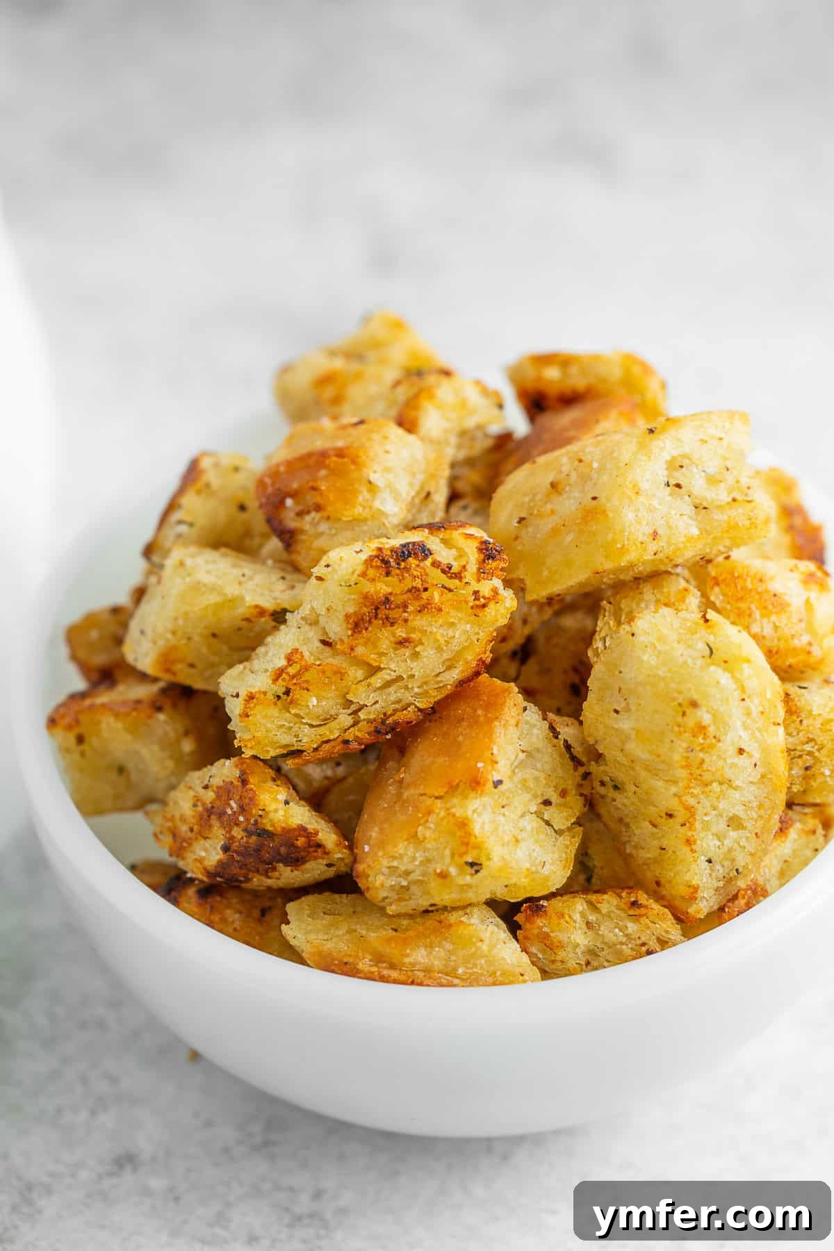 Golden Garlic Butter Croutons 4 A small white bowl generously filled with golden, crispy homemade garlic butter croutons, ready to be served or added to a dish.