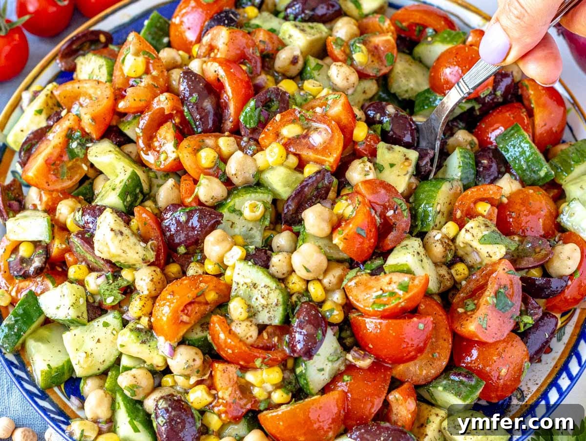 40 Flavorful Plant-Based Dinners 41 Colorful chickpea salad served on a blue plate, with a hand holding a spoon.
