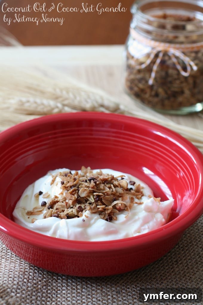 Delicious Coconut Oil & Cocoa Nib Granola Close-up of freshly baked coconut oil and cocoa nib granola spread on a parchment-lined baking sheet, showing crispy clusters and rich textures of the various ingredients.