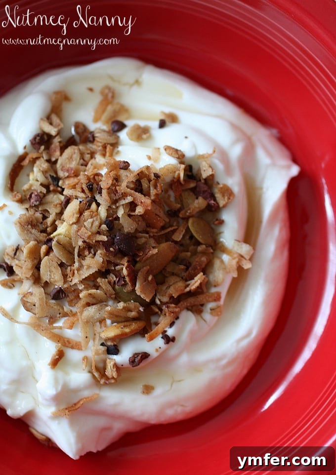 Healthy Granola Ingredients A vibrant display of unbaked coconut oil and cocoa nib granola mixture in a large bowl, featuring rolled oats, shredded coconut, chopped almonds, and raw cocoa nibs.