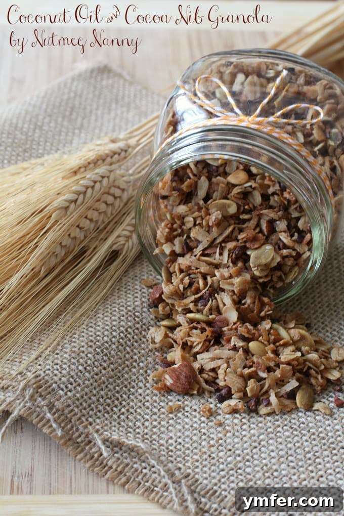 Serving Coconut Oil & Cocoa Nib Granola A generous spoonful of warm, toasted homemade granola featuring shiny golden oats, creamy white coconut flakes, and dark cocoa nibs. The granola is glistening slightly with maple syrup and coconut oil.
